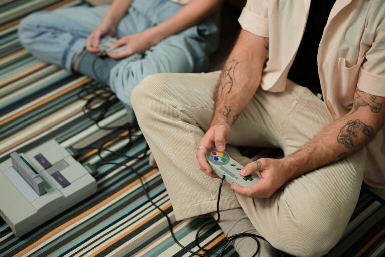 Two adults playing with a retro gaming console on a striped carpet indoors.
