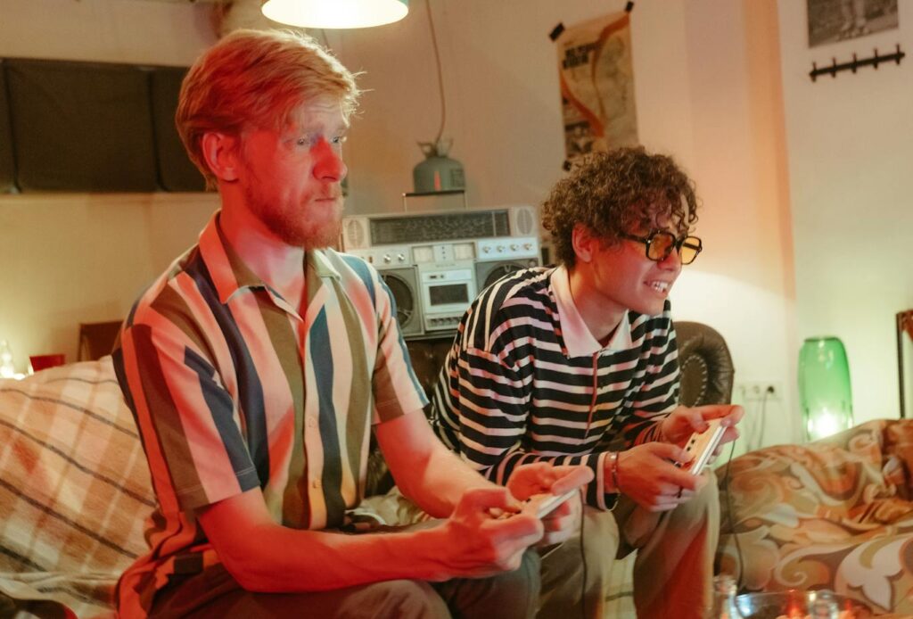 Two teenagers playing a retro video game console indoors, capturing nostalgic 80s vibe.